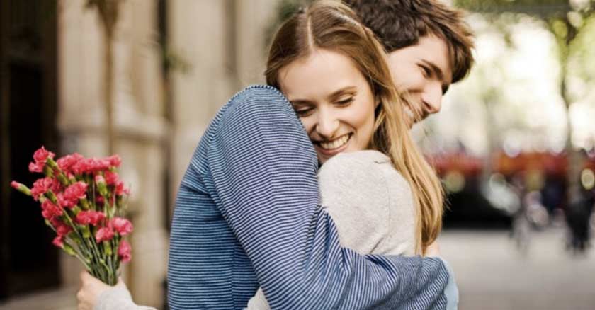 hombre abrazando a una esposa felices sonrisas ramo de rosas